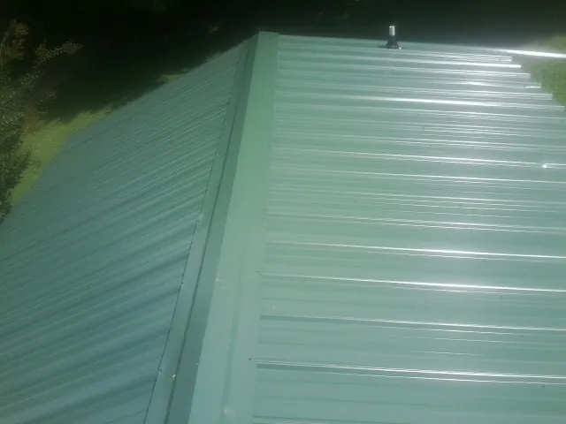 New green metal panels meeting at the ridge of a roof — Flat Roof Repair work by our crew in Perris