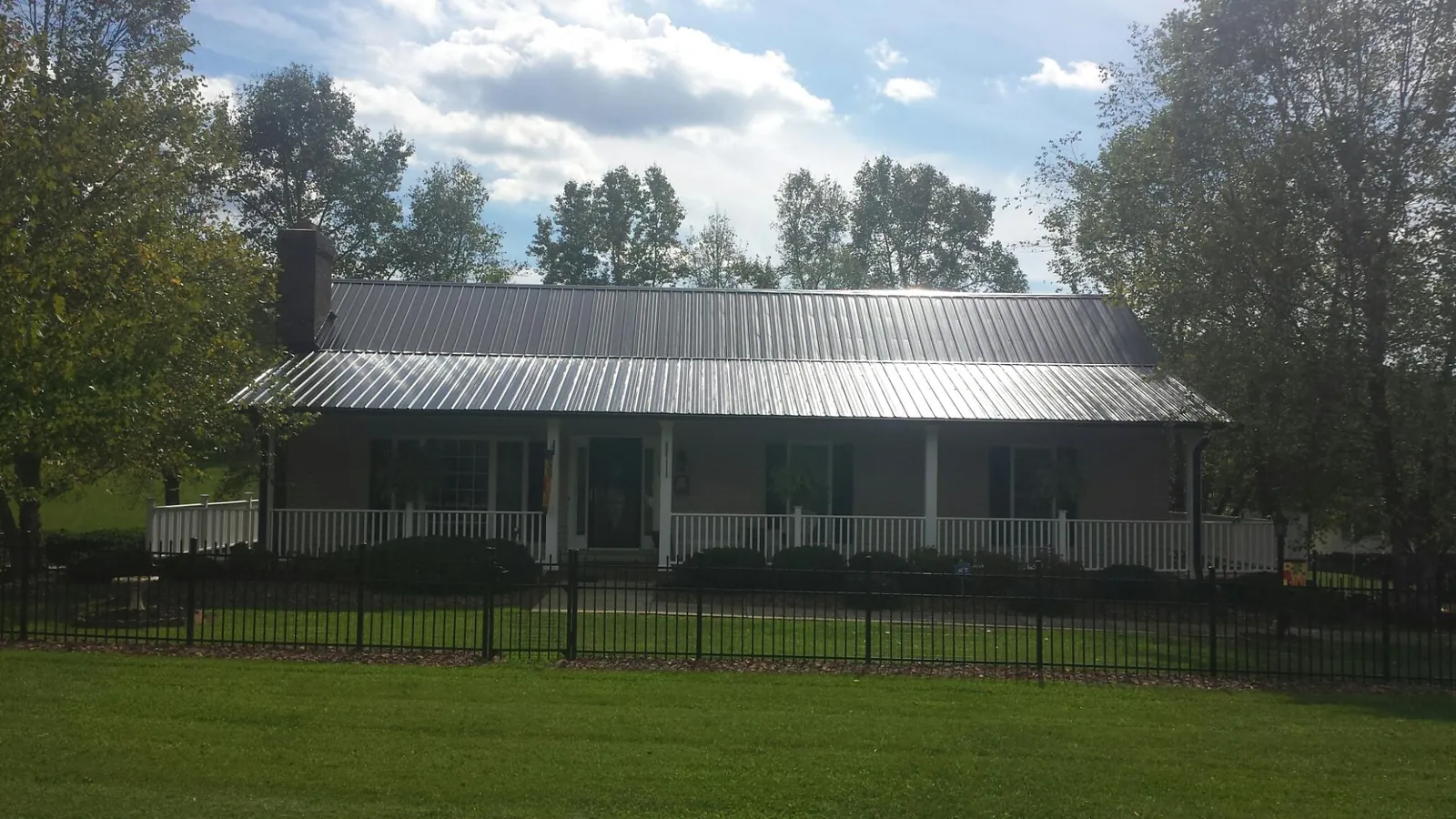 Gray metal roof on a brick ranch with a full width front porch — Gutter Guard Installation work by our crew in Perris